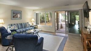 Una sala de estar con un sofá, sillones, una mesa de centro y un televisor.