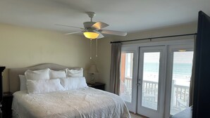 A bedroom with a bed, a ceiling fan, a nightstand, a lamp, and a view of the outside through a sliding door. - Beautiful Gulf-Front Duplex  in Morgantown. Gulf Shores, AL (Gulf Shores)
