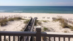 A beach with a wooden boardwalk leading to the water, surrounded by sand and sparse vegetation. - Beautiful Gulf-Front Duplex  in Morgantown. Gulf Shores, AL (Gulf Shores)