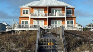 A two-story building with a wooden deck leading to the entrance. - Beautiful Gulf-Front Duplex  in Morgantown. Gulf Shores, AL (Gulf Shores)