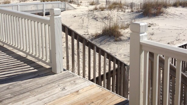 A wooden deck with white railings overlooking a beach with sand dunes and the ocean. - Beautiful Gulf-Front Duplex  in Morgantown. Gulf Shores, AL (Gulf Shores)