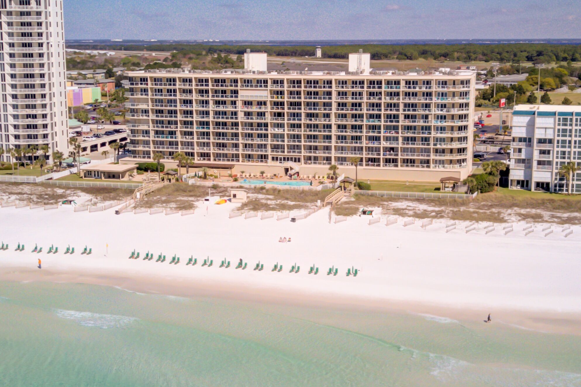 A multi-story hotel with a pool area and beach access.