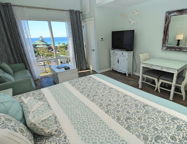 Une chambre d’hôtel avec un lit, un bureau, une télévision et une vue sur l’océan.