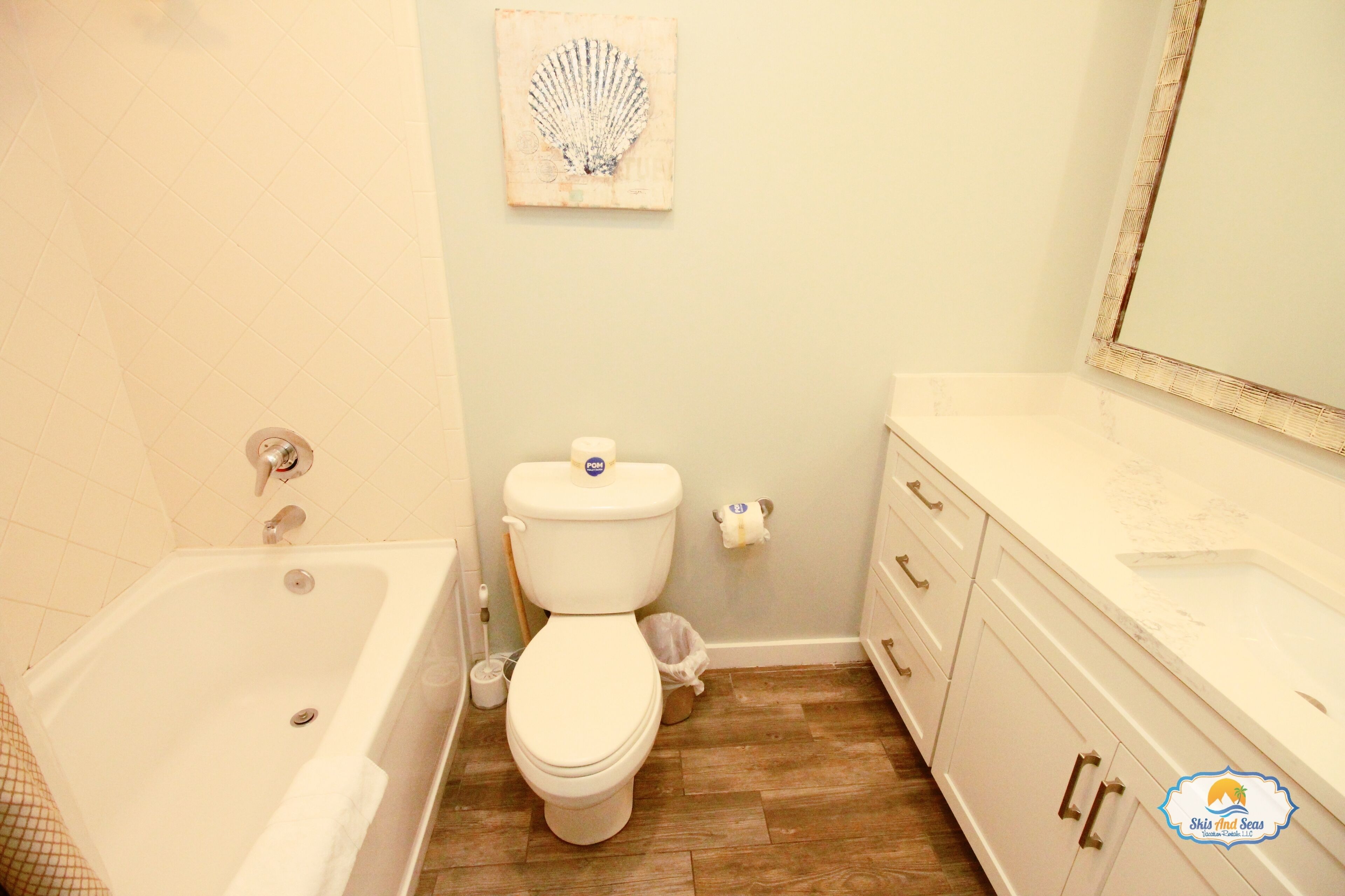 A bathroom with a bathtub, toilet, vanity, and a mirror.