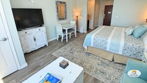 Una habitación de hotel con cama, escritorio, televisión y espejo.