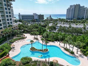 Un resort con una piscina grande rodeada de palmeras y vistas al océano.