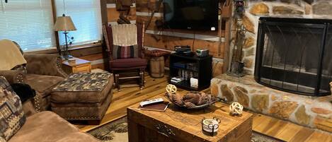 A cozy living room with a stone fireplace, a television, and a wooden coffee table.