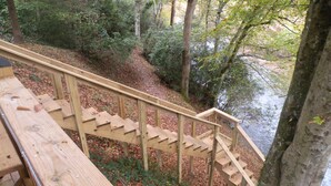 Eine Holztreppe führt zu einem bewaldeten Gelände mit einer Holzterrasse.