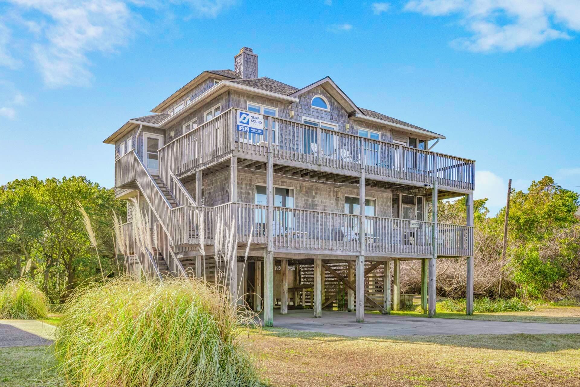 A two-story wooden building with a balcony, a sign indicating 'Surf Sound 112', and a staircase leading to the upper level.
