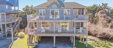 A two-story wooden building with balconies, a covered deck, and a staircase.
