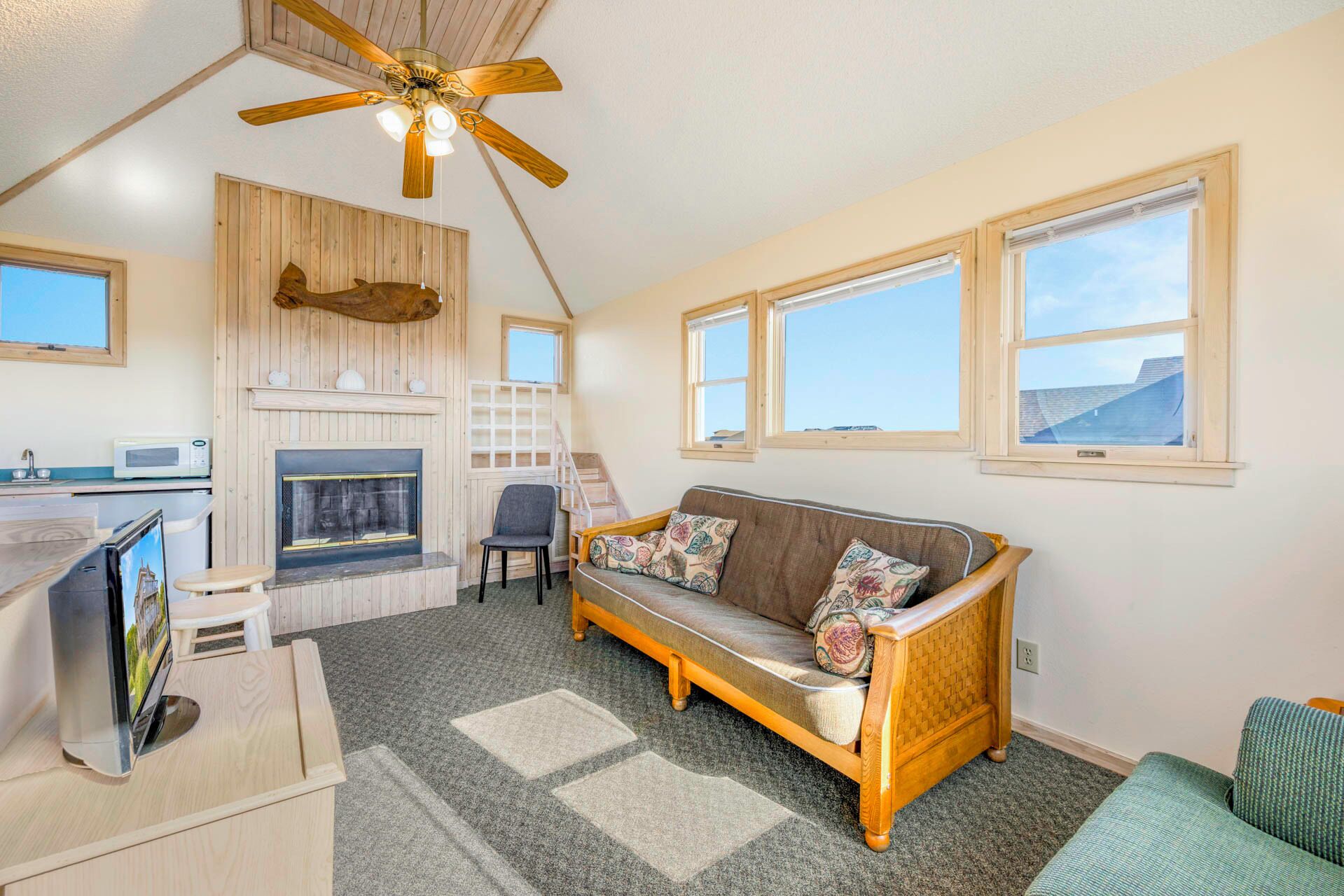 A cozy room with a wooden ceiling fan, a fireplace, a sofa, and a television.