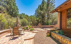 Une terrasse avec une table et des chaises, entourée d’une zone recouverte de gravier et agrémentée de plantes en pot.