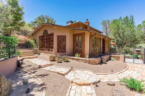 A house with a patio, large windows, and a garden. -  Peaceful, private, secluded wooded sanctuary located in the heart of Sedona. 5* (Sedona)