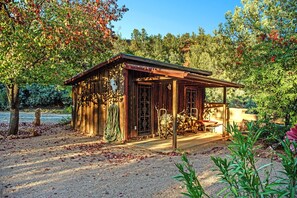 Un chalet rustique en bois, doté d’un porche, entouré d’arbres et bordé d’un chemin de gravier.