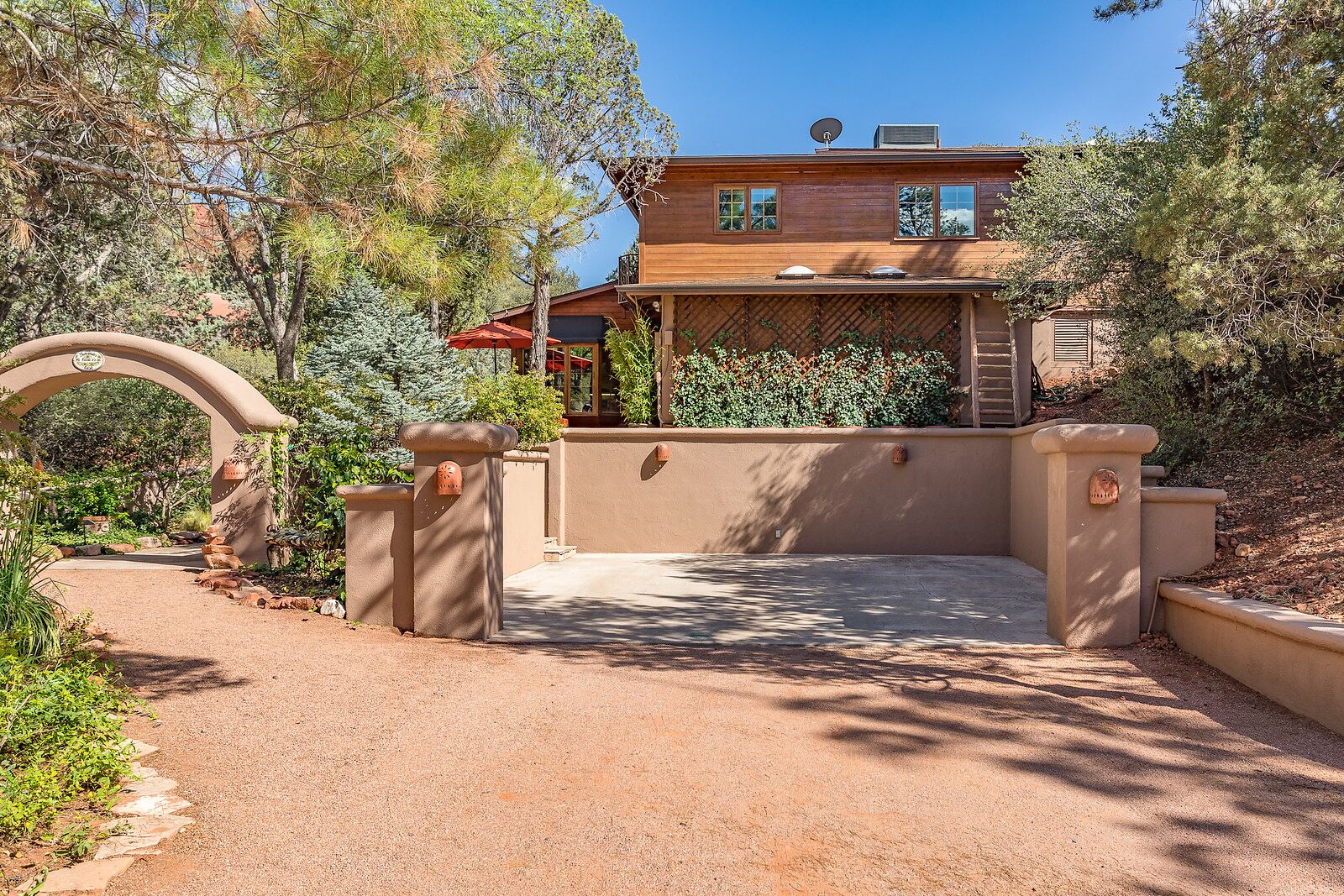 A rustic wooden house with a covered patio and a gravel driveway.