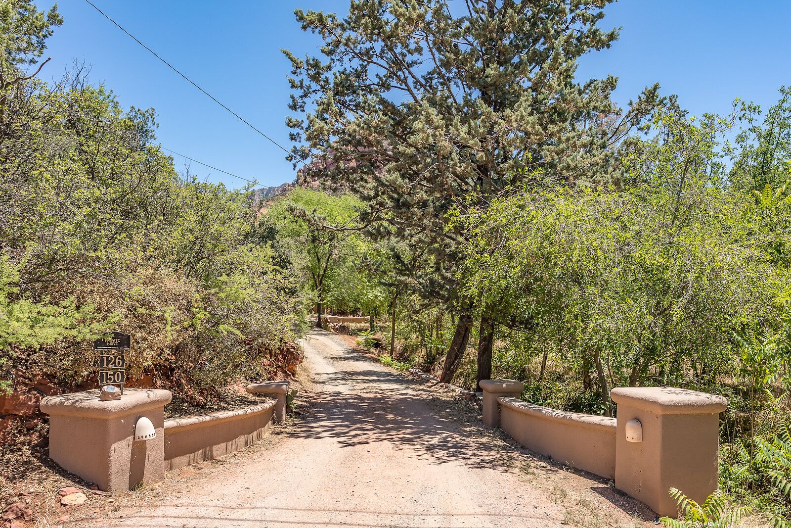 Un sendero de tierra que serpentea por una zona boscosa, con un cartel que indica las rutas 126 y 150.