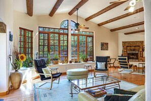 A spacious living room with large windows, wooden beams, a fireplace, and comfortable seating. -  Peaceful, private, secluded wooded sanctuary located in the heart of Sedona. 5* (Sedona)