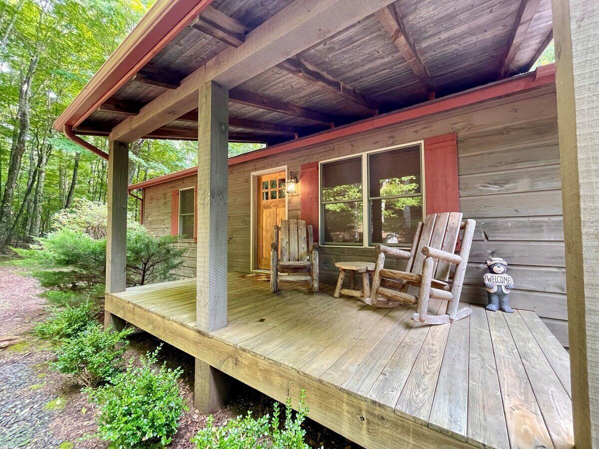 A wooden cabin with a porch, a door, and a welcome sign.