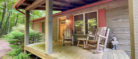 A wooden cabin with a porch, a door, and a welcome sign.