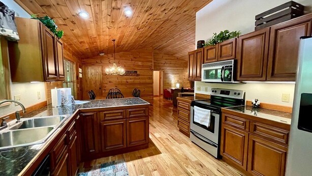 A kitchen with wooden cabinets, a central island, stainless steel appliances, and a wooden ceiling.