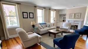 A living room with a wooden floor, white sofas, a blue armchair, and a fireplace. - Welcome to the iconic Pink Lady (Lewes)