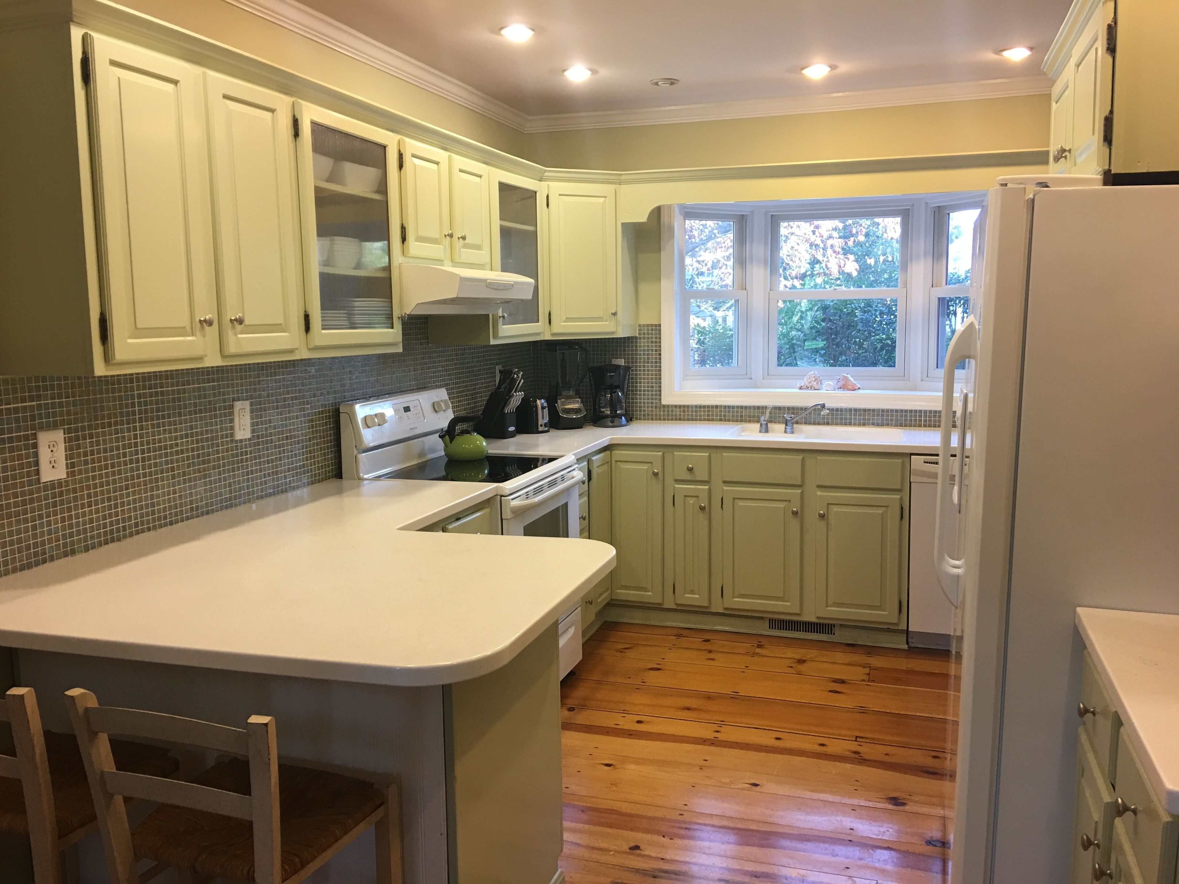 A kitchen with a central island, a stove, a sink, and a refrigerator.