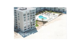 A high-rise building with a rooftop pool and a landscaped area with palm trees.