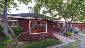 A log cabin with a porch, a small deck, and a large window.