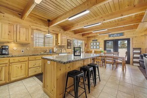 Interior de madeira com cozinha, bar e área de refeições.