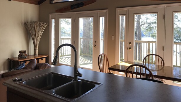 A kitchen with a double sink, wooden ceiling, and large windows overlooking a deck. -  Lake Front Home with community boat ramp. Private,  close to marinas and town. (Somerset)