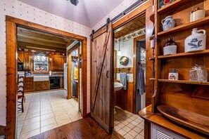 A rustic kitchen with wooden cabinets, a large wooden door, and a tiled floor. - DOGWOOD LODGE • TIMBERIDGE (SPARED)• (Gatlinburg)