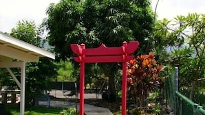 A red torii gate at the entrance of a garden area with a pathway leading through it.