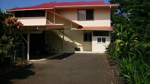 A two-story house with a red roof, a covered porch, and a driveway.