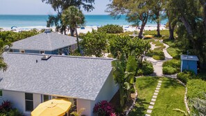 A residential property with a view of the beach, a paved pathway, and a small garden area.