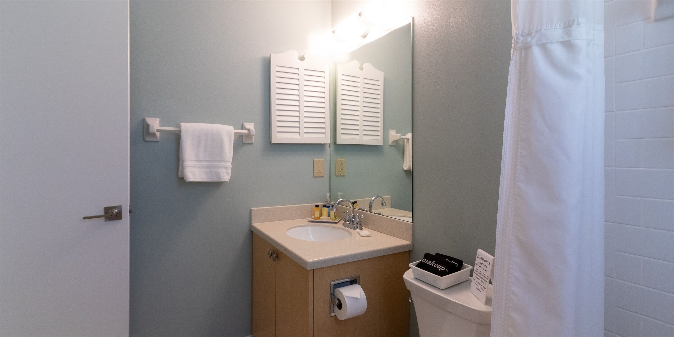 A bathroom with a sink, mirror, towel rack, and toiletries.