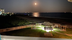 Une vue nocturne d’une plage avec un kiosque et une clôture.