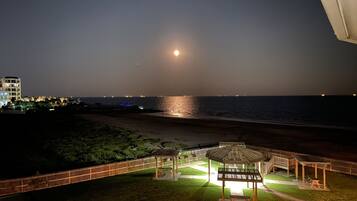 Une vue nocturne d’une plage avec un kiosque et une clôture.