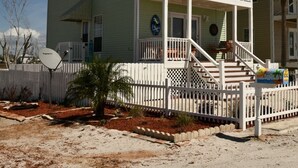 A two-story building with a balcony, a satellite dish, and a small garden area. - Bettie's Beach House (Mexico Beach)