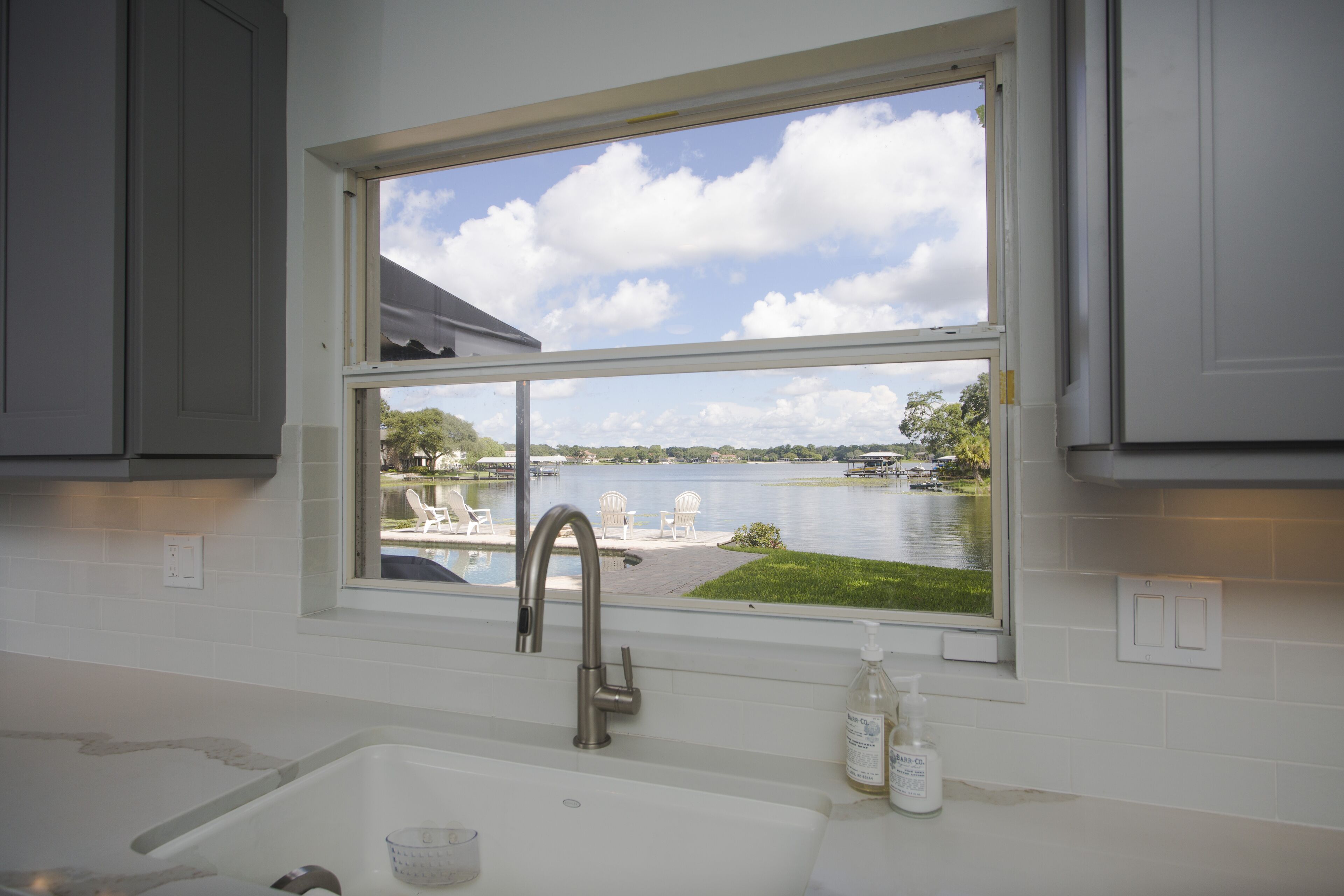 A kitchen with a window overlooking a lake, a sink, and a bottle of hand soap.