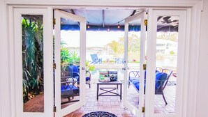 An open patio with blue chairs and a table, a Monopoly Battleship game, and a view of the outside. - Lakefront Pool Home w/ Game Room, Epic View, Kayaking (Tampa)