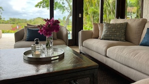 Ein Zimmer mit einer Couch, einem Couchtisch mit Tablett und einer Vase mit Blumen.