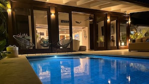 Ein Schwimmbecken mit Fliesenrand, umgeben von Liegestühlen und einer Liege.