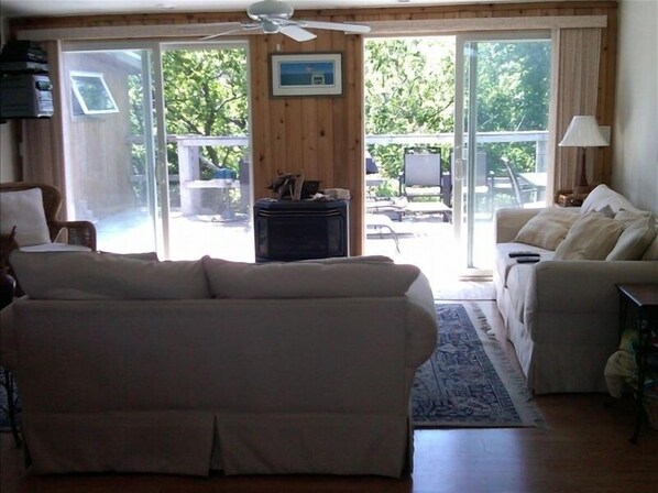 A living room with a sofa, a coffee table, and a lamp. There is a sliding glass door leading to an outdoor area with a patio table and chairs.