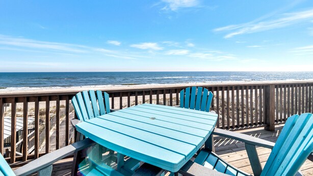 Een houten terras met een tafel en stoelen, met uitzicht op de oceaan.