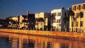 A waterfront with buildings along the shore, a stone wall, and palm trees. - 1 Bedroom Cottage in the Old Historic District. Free Street Parking.  (Charleston)