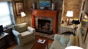 A cozy living room with a fireplace, two armchairs, a coffee table, and a television. - 1 Bedroom Cottage in the Old Historic District. Free Street Parking.  (Charleston)
