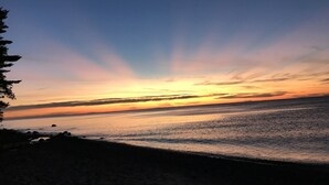 Una playa al atardecer con cielo despejado y mar tranquilo.