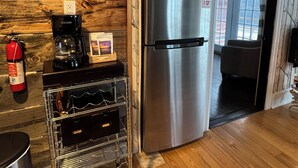 Una cocina con un refrigerador de acero inoxidable, una cafetera y un enfriador de vino sobre una encimera de madera.