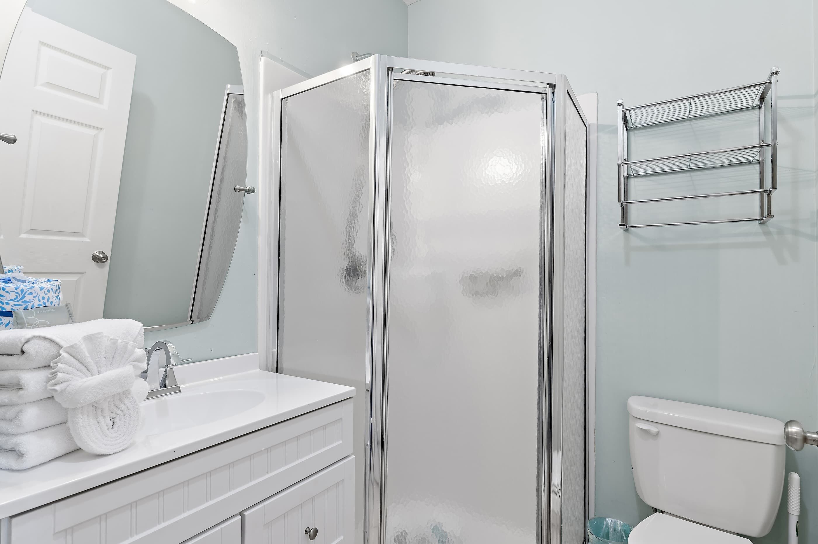 Une salle de bain avec une douche à parois de verre, un lavabo blanc et des toilettes.