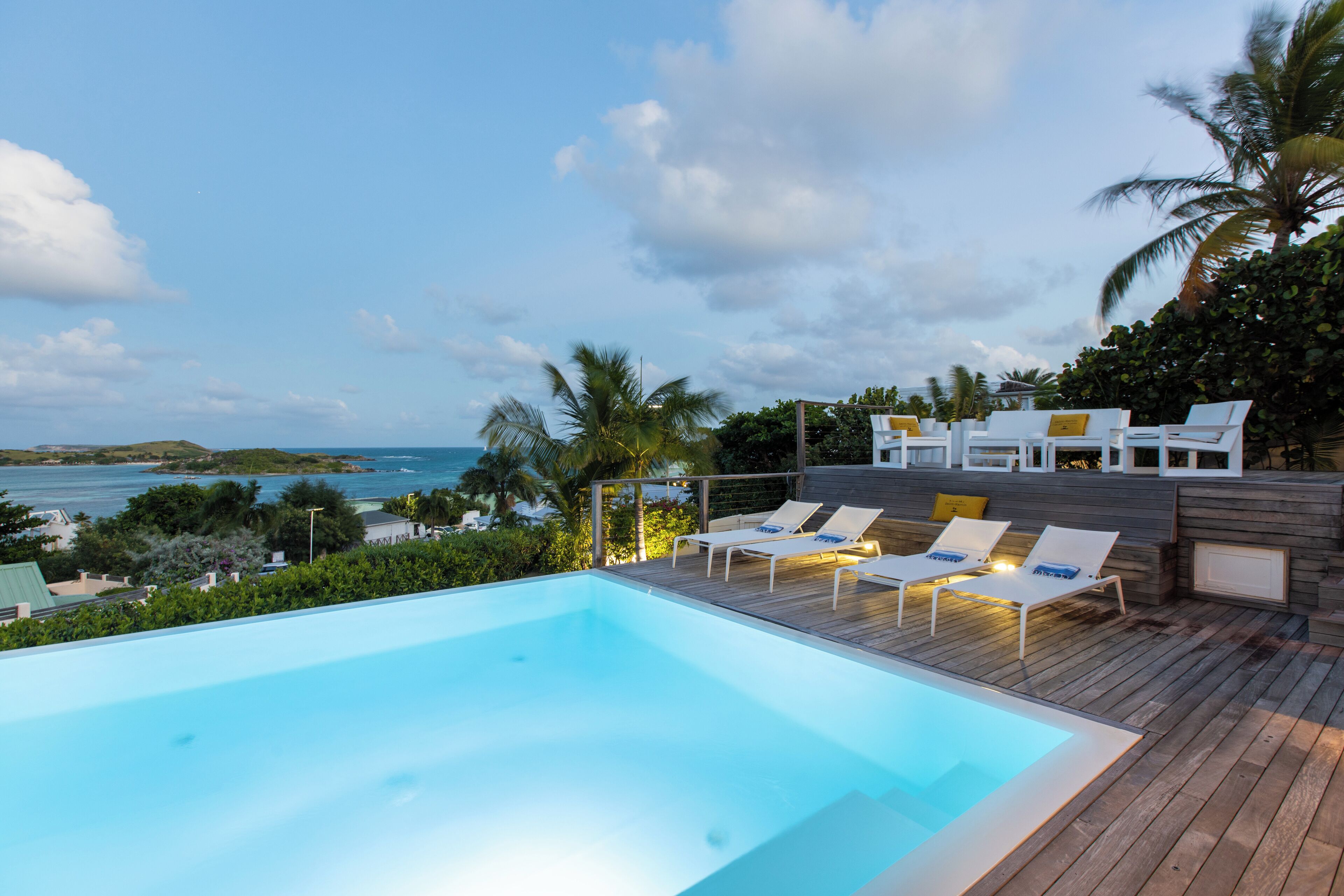 A swimming pool with lounge chairs and a view of the ocean.